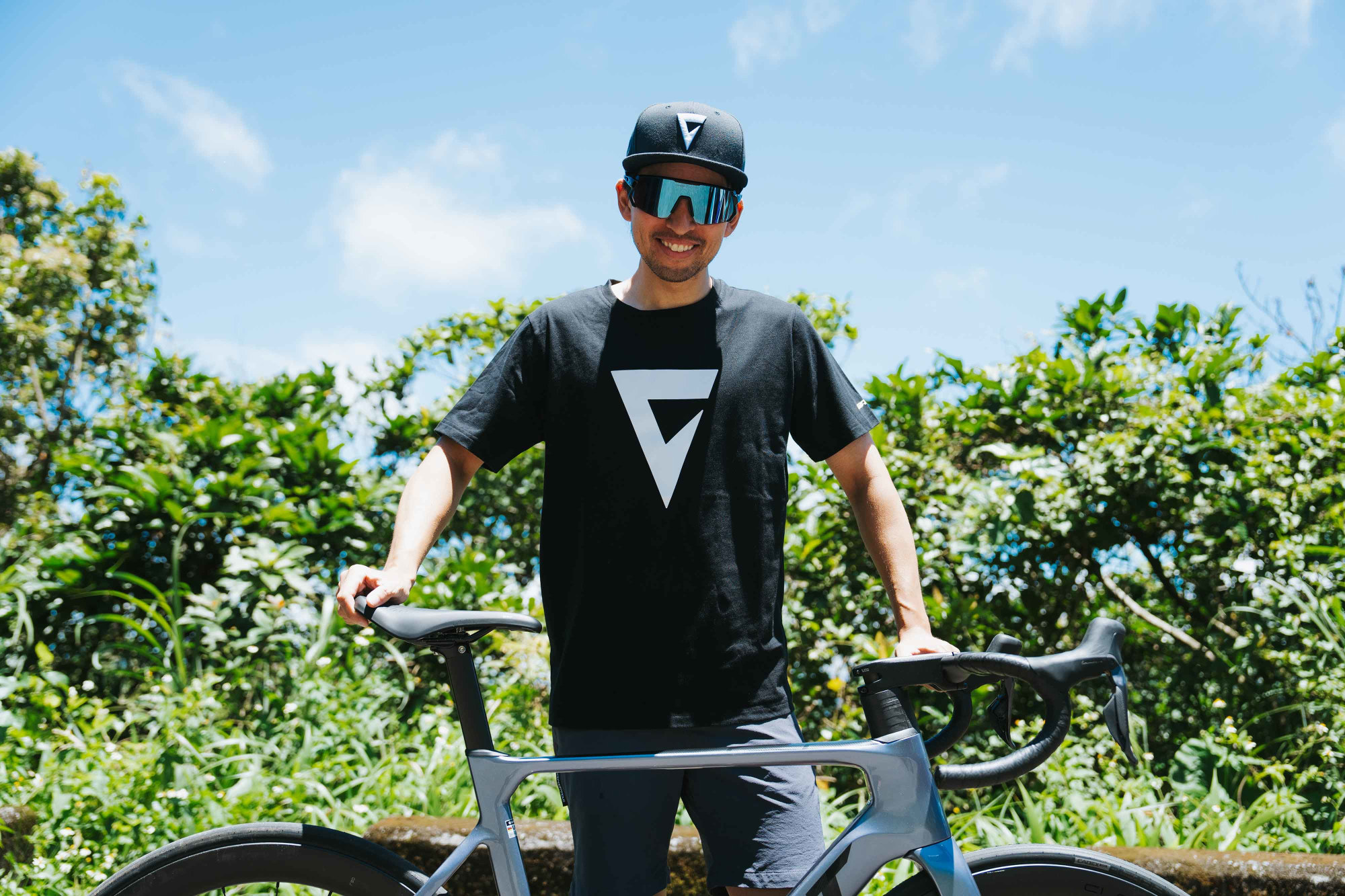 Giant Rush Mark T‑Shirt in Schwarz mit grossem Frontlogo neben einem Rennrad im Freien.