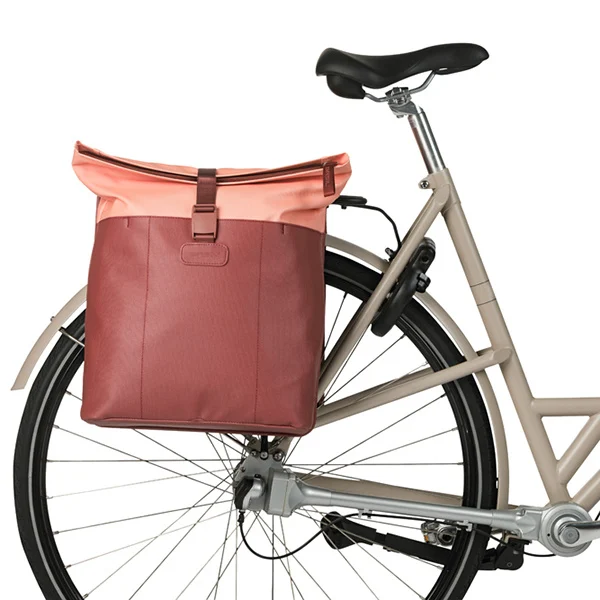  Basil Vive MIK Doppelpacktasche in Burgund/Pink montiert auf dem Gepäckträger eines Citybikes.