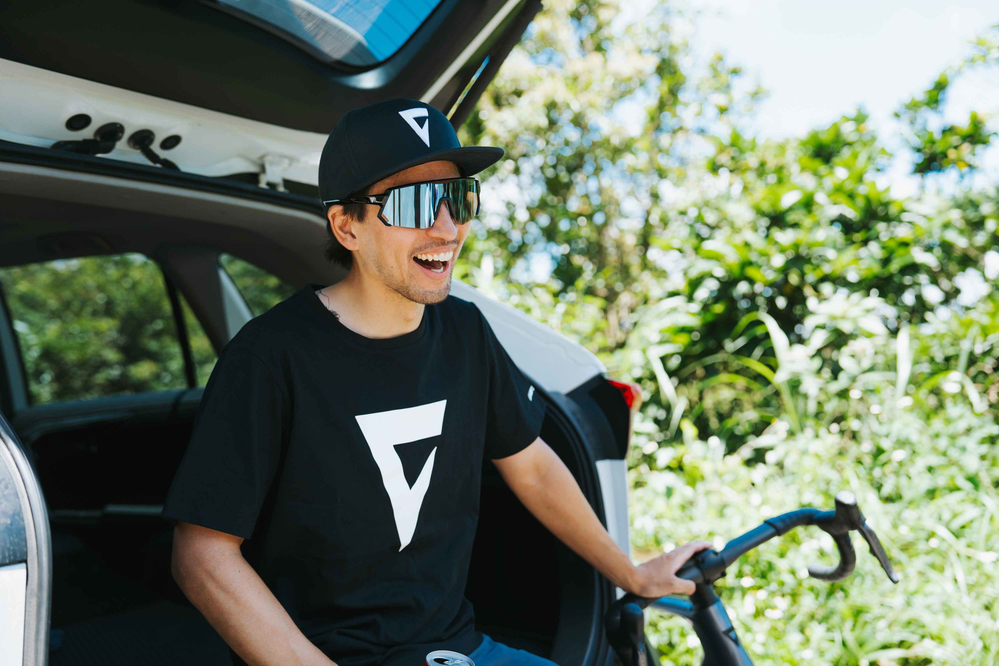 Giant Rush Mark T‑Shirt in Schwarz mit grossem Frontlogo in Lifestyle‑Szene am Fahrzeug.