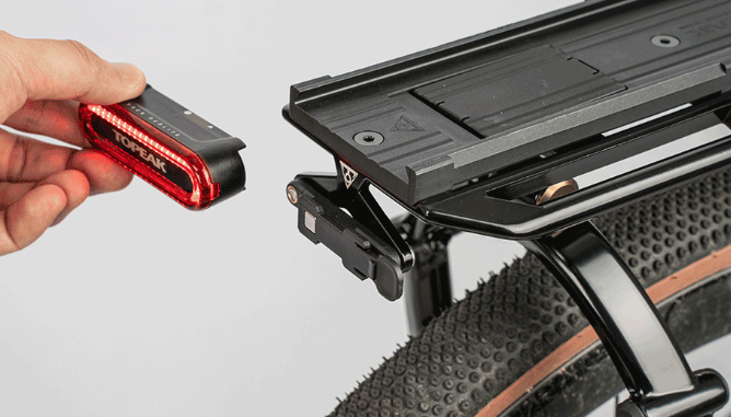 Topeak Rack Redlite Ruecklicht in Schwarz-Rot beim Abnehmen von der Halterung am Gepaecktraeger.