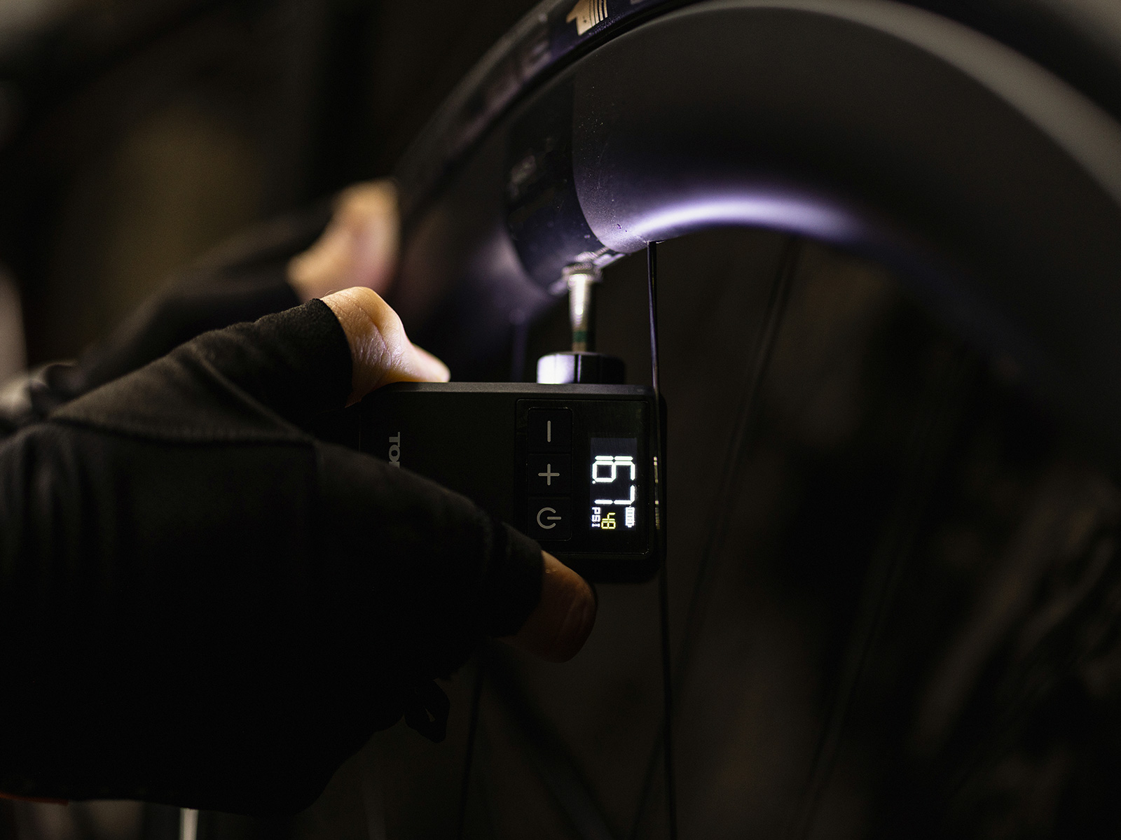 Topeak E-Booster Digital Mini Elektornische Fahrradpumpe, in Benutzung im Dunkeln beim Aufpumpen eines Reifens