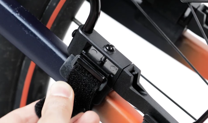 Nahaufnahme der Montage des Topeak TetraFender M2, Hand befestigt Klettgurt an der Sitzstrebe.