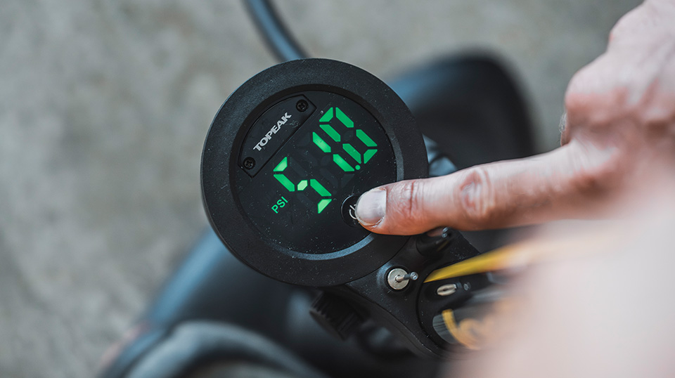 Finger drückt den Power-Button am LED-Digitaldisplay der Topeak Joeblow Sport Digital 2.0 – Anzeige zeigt 51.0 PSI.