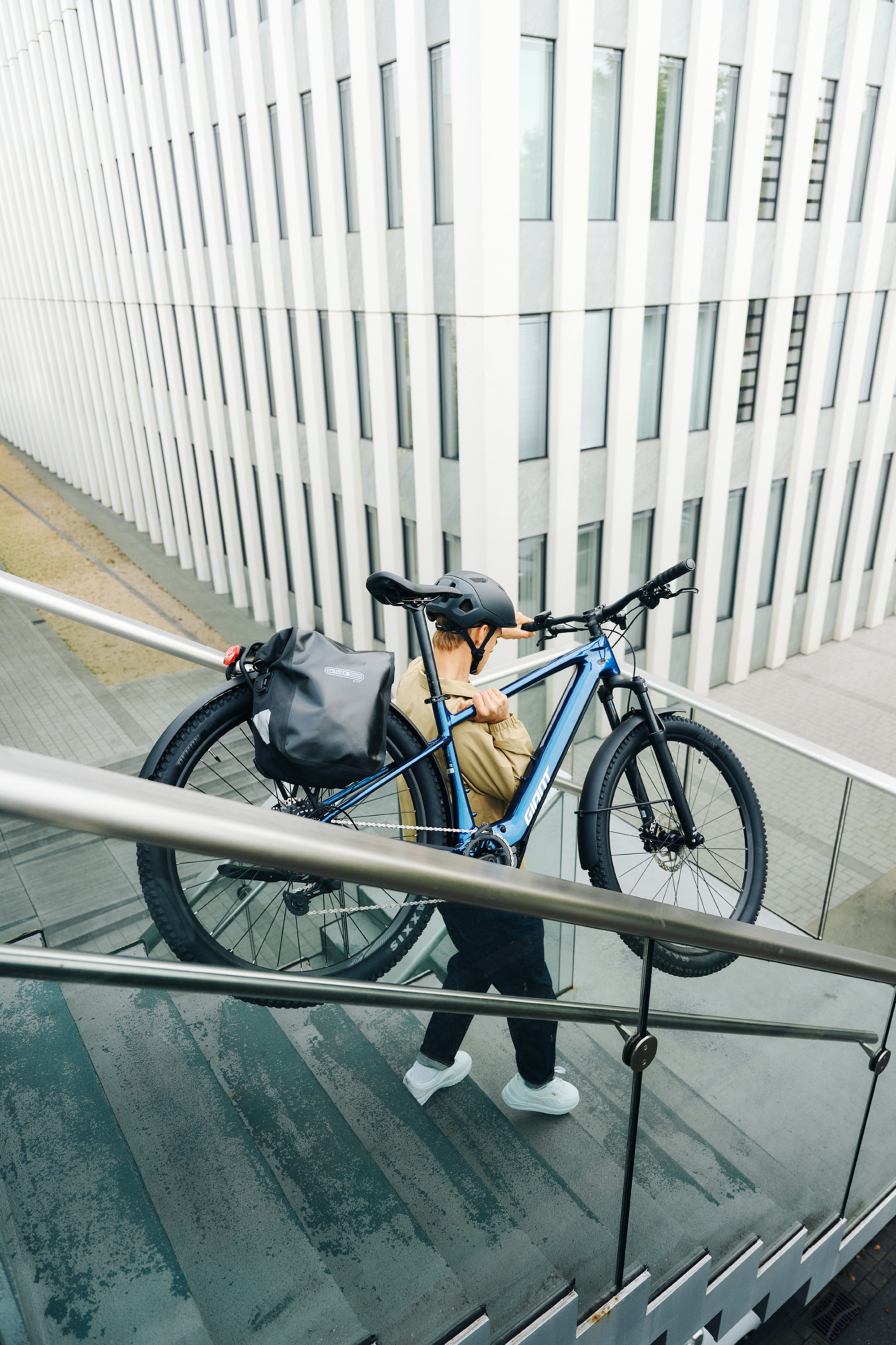 Ein junger Mann trägt das MTB Giant Talon E-Bike in einer urbanen Umgebung eine Treppe herunter